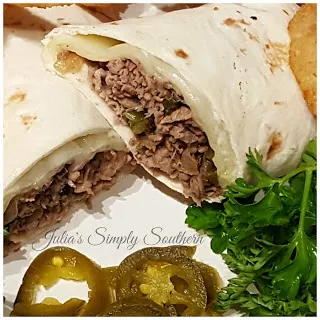 Philly cheesesteak wrap on a plate with onion rings