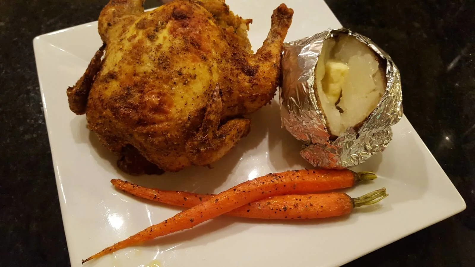 Cornish game hen with baked potato and roasted carrots