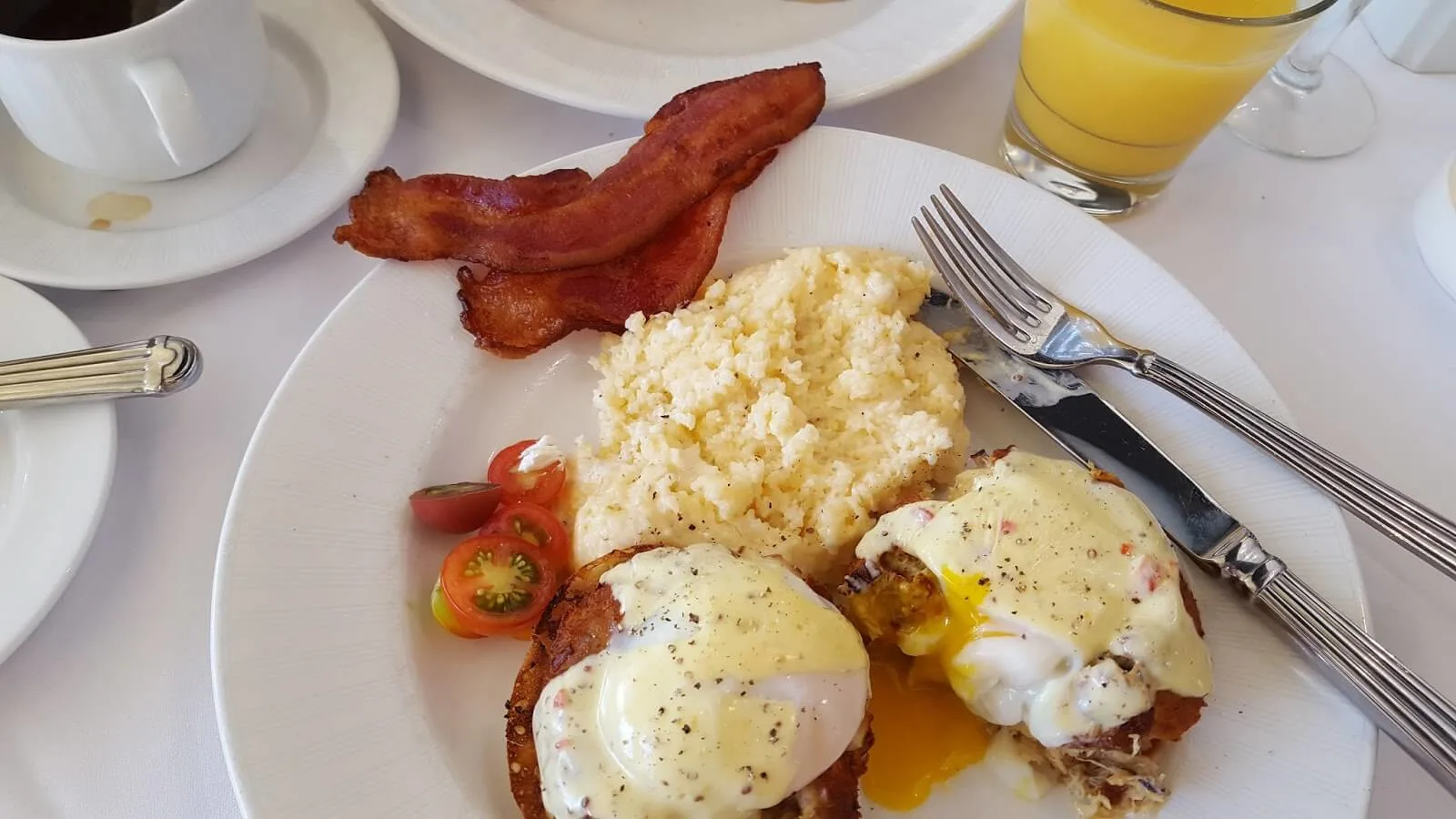 Amazing crab Benedict with grits and smoked bacon for brunch on a white plate - traveling to Charleston SC 