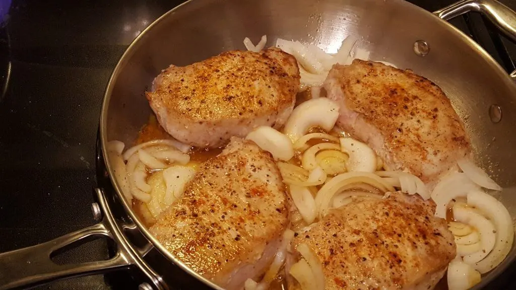 Sautéing pork chops and onions in a skillet