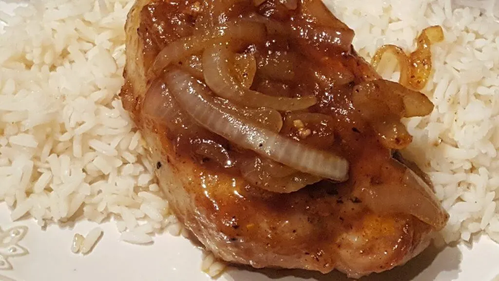 cooked glazed pork chop on a bed of rice