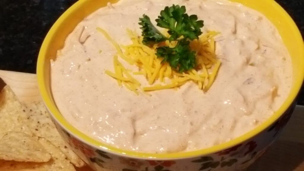 Taco Dip Appetizer in a yellow bowl garnished with shredded cheese and parsley
