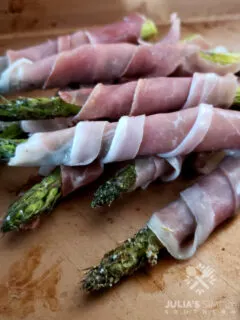 Asparagus Wrapped in Prosciutto on a sheet pan serving tray