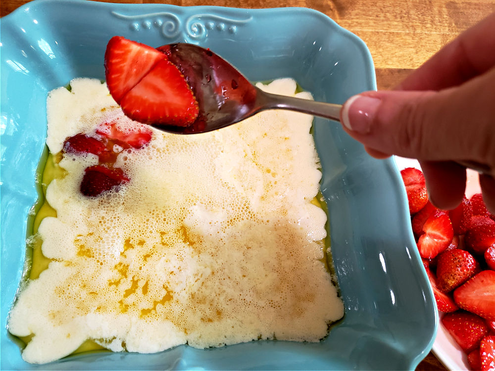 Adding sliced juicy strawberries to the cobbler batter for baking
