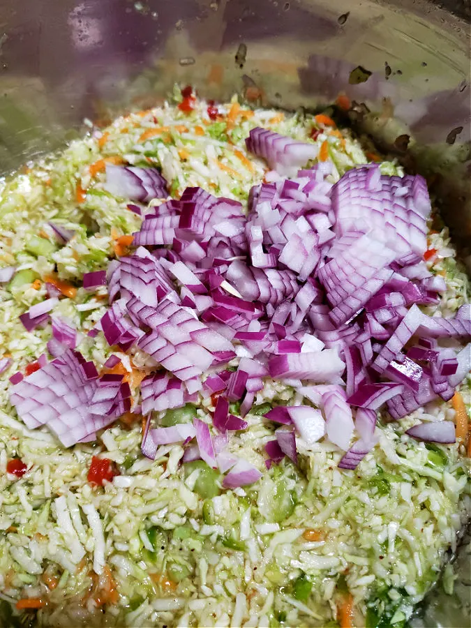 Adding red diced onion to the Amish coleslaw mixture