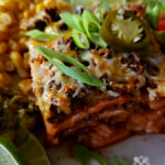 Delicious Enchilada Casserole Recipe garnished with scallions and a sliced pickled jalapeno