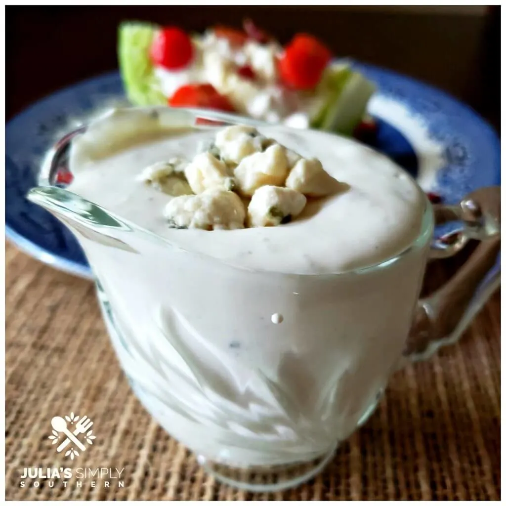 Glass serving bowl with Blue Cheese Dressing and a wedge salad in the background