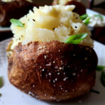 Fluffy Baked Russet Potatoes served on a white plate garnished with scallions