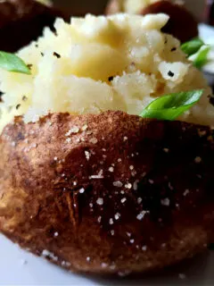 Fluffy Baked Russet Potatoes served on a white plate garnished with scallions