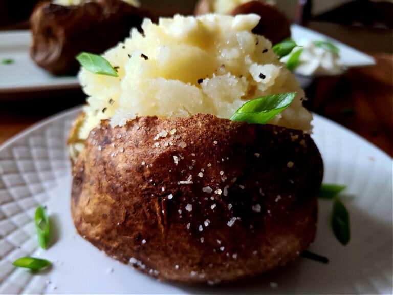 Fluffy Baked Russet Potatoes served on a white plate garnished with scallions