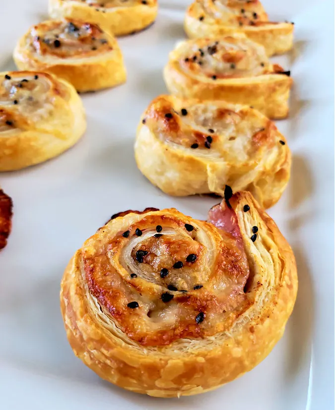 Roll Ups puff pastry pinwheels appetizers with ham and cheese on a white platter