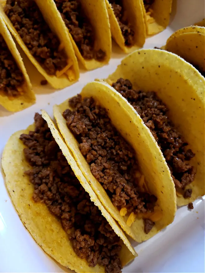 Layering shredded cheese and cooked ground beef with taco seasoning before baking