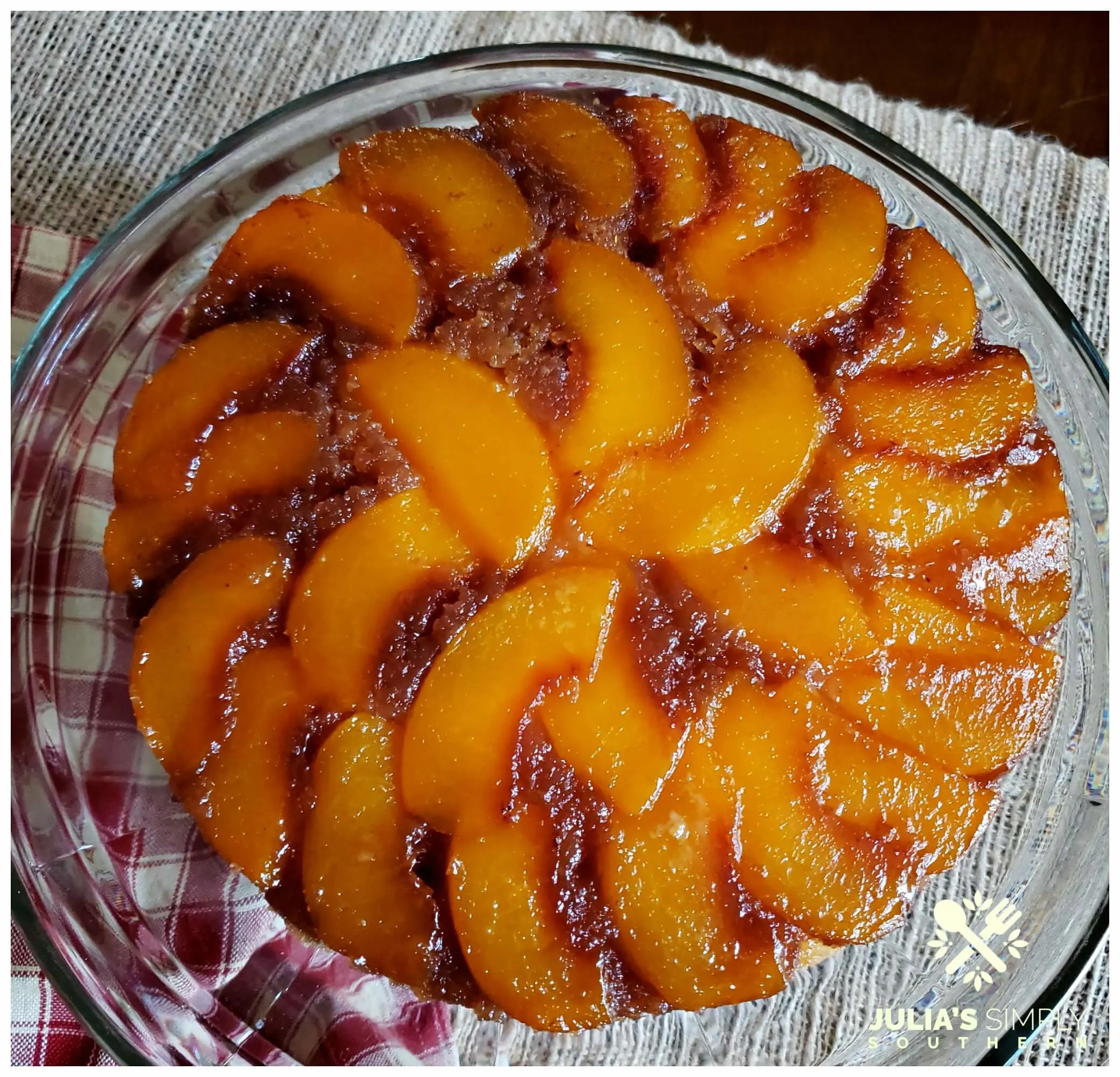 Beautiful caramel peach upside down cake with freestone Pretty Lady Peaches on a glass plate and country check napkin