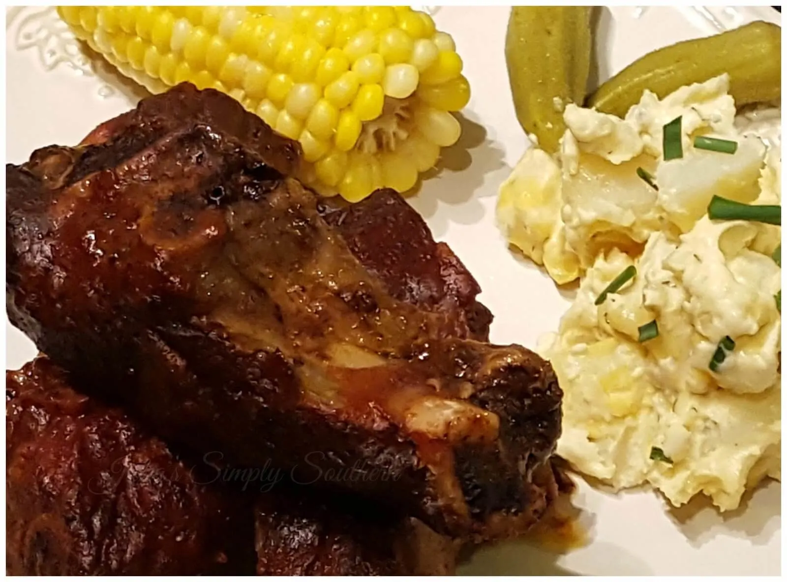 Beef ribs with corn on the cob, potato salad and pickled okra