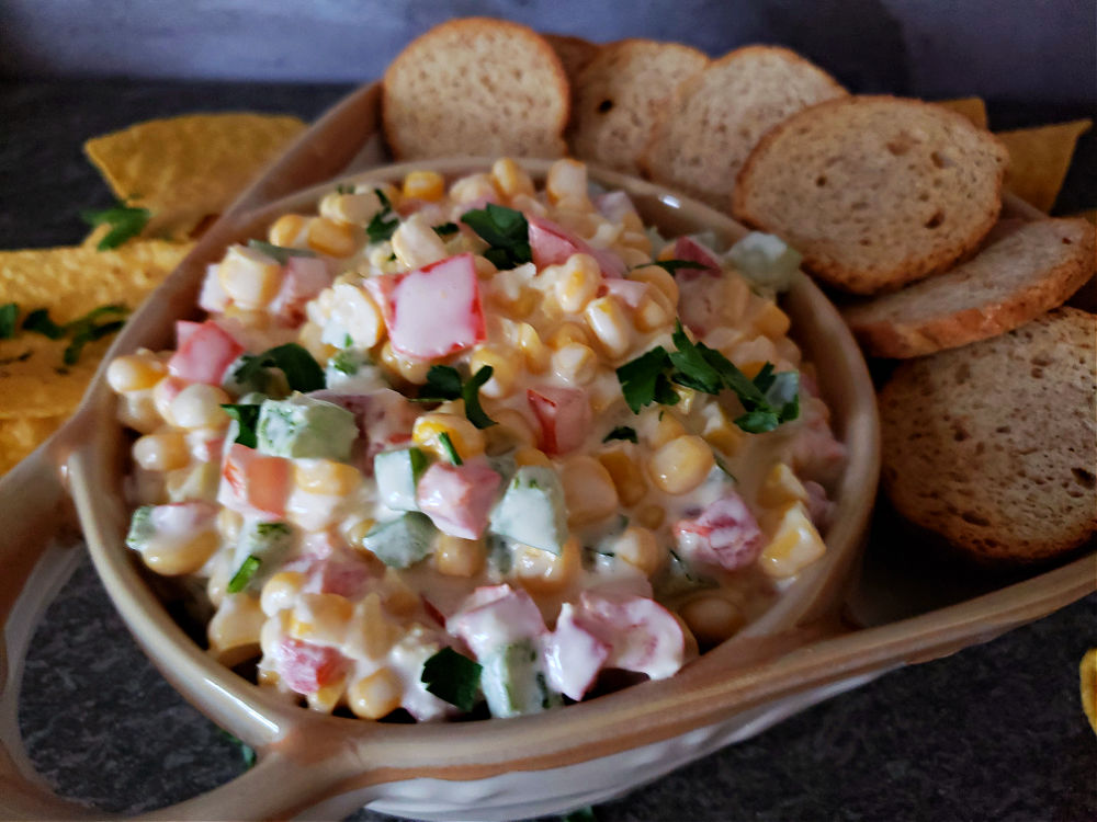 creamy corn dip garnished with parsley in a stoneware serving dish