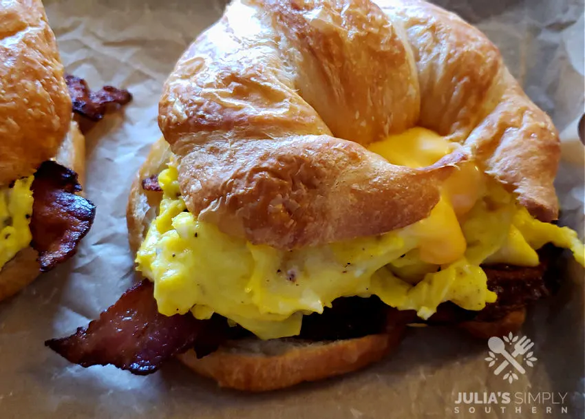 bacon egg and cheese croissant sandwiches on a sheet pan lined with parchment