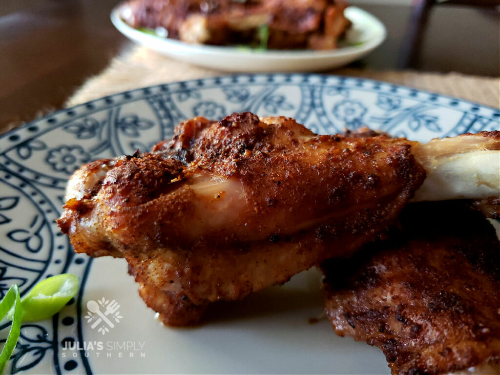 Crispy oven baked roast turkey wings on a blue and white plate garnished with scallions