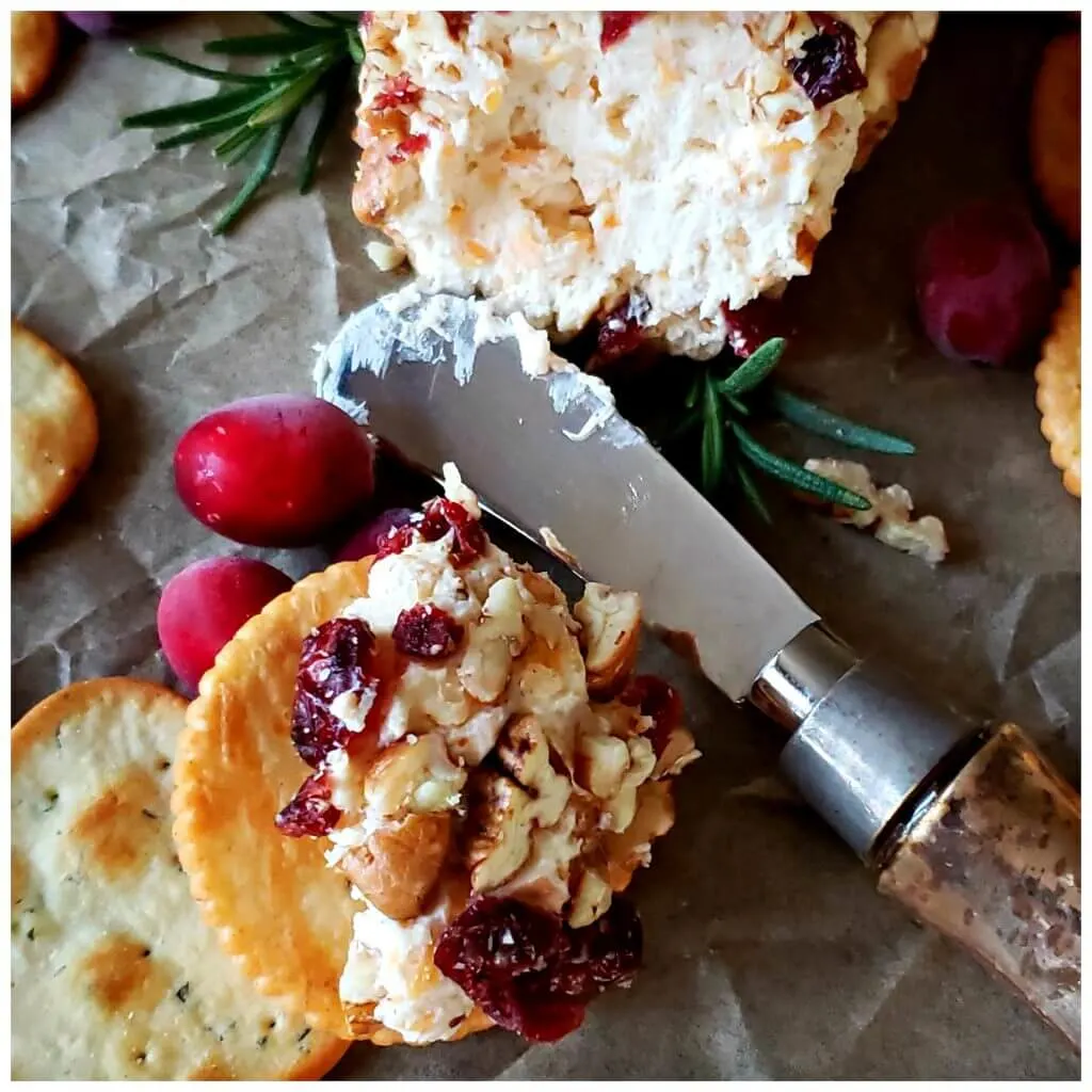 spreading holiday cheese ball appetizer on a cracker