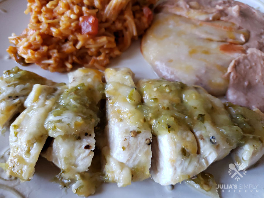 Amazing salsa verde chicken dinner topped with cheese and served with Spanish rice and refried beans