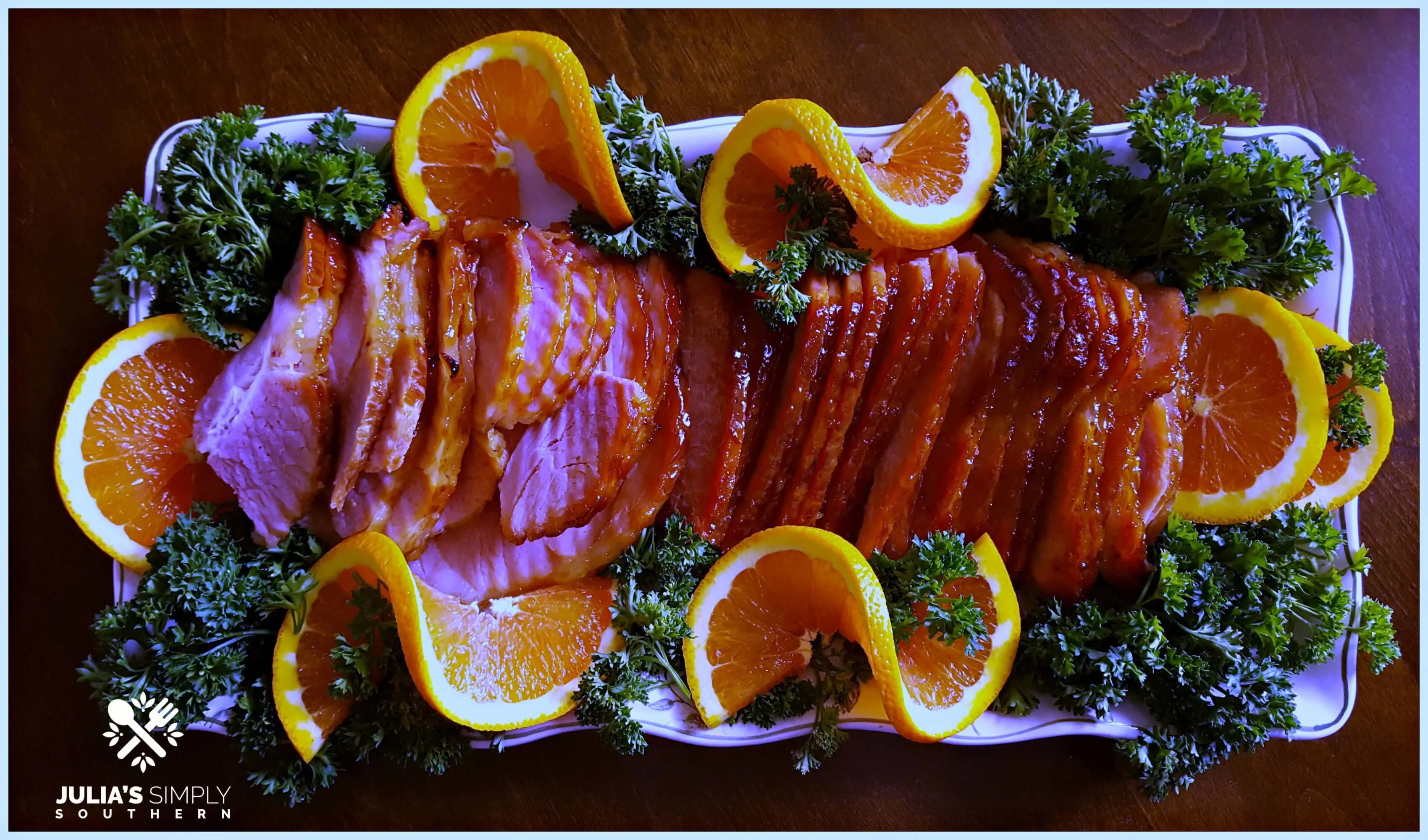Glazed Ham Recipe for Glazed Ham with a Honey Orange Glaze on a serving platter garnished with orange slices and parsley