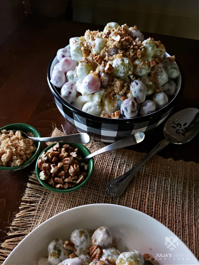 Serving Bowl with grape salad with smaller bowls with brown sugar and pecan garnish