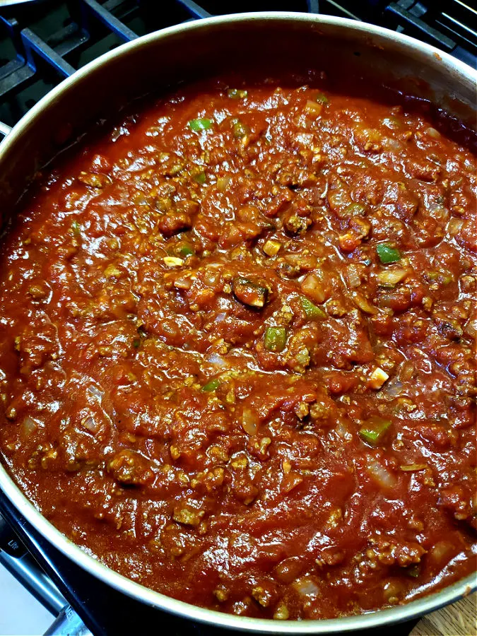 Easy homemade spaghetti sauce recipe simmering on the stove top, using crushed tomatoes - not whole tomatoes.