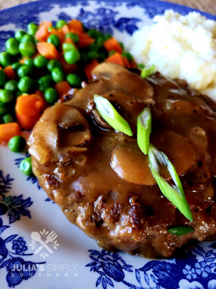 Blue and white plate with Salisbury Steak and mushroom gravy garnished with scallions
