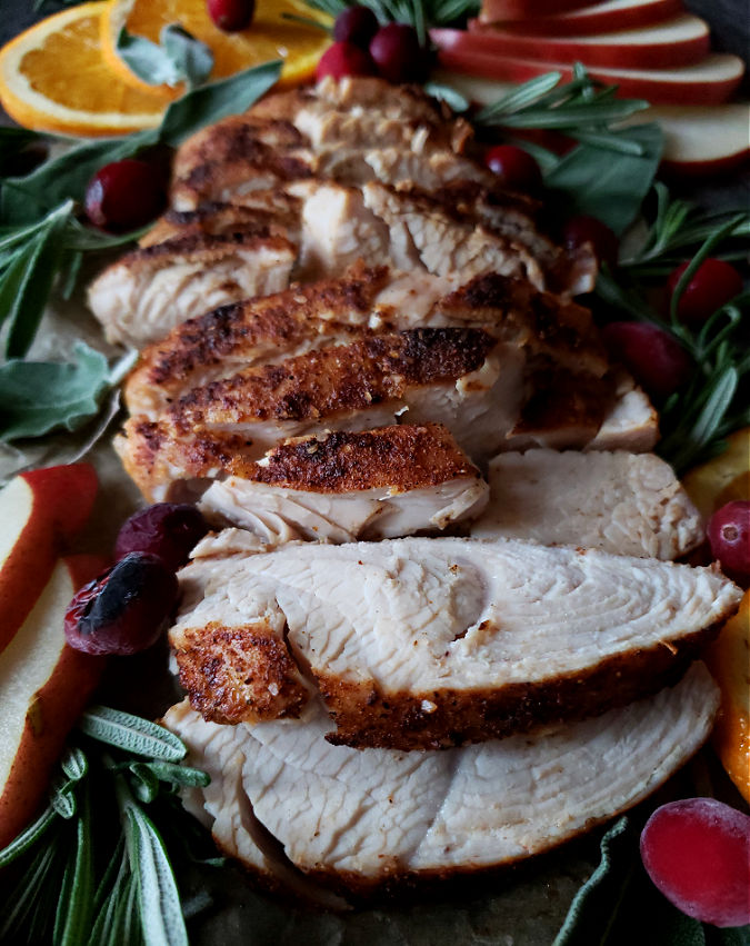 turkey breast tenderloin air fryer recipe with wonderful seasonings, sliced on a platter with orange slices, herbs and cranberries