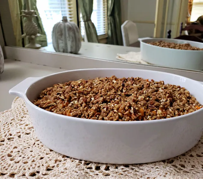 homemade sweet potato soufflé made from fresh sweet potatoes with raisins and coconut and pecan topping on the food serving table in the dining room
