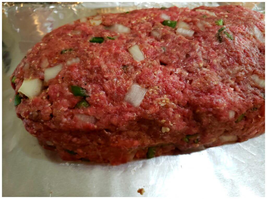 A sheet pan lined with aluminum foil and a hand formed classic southern meatloaf ready for baking