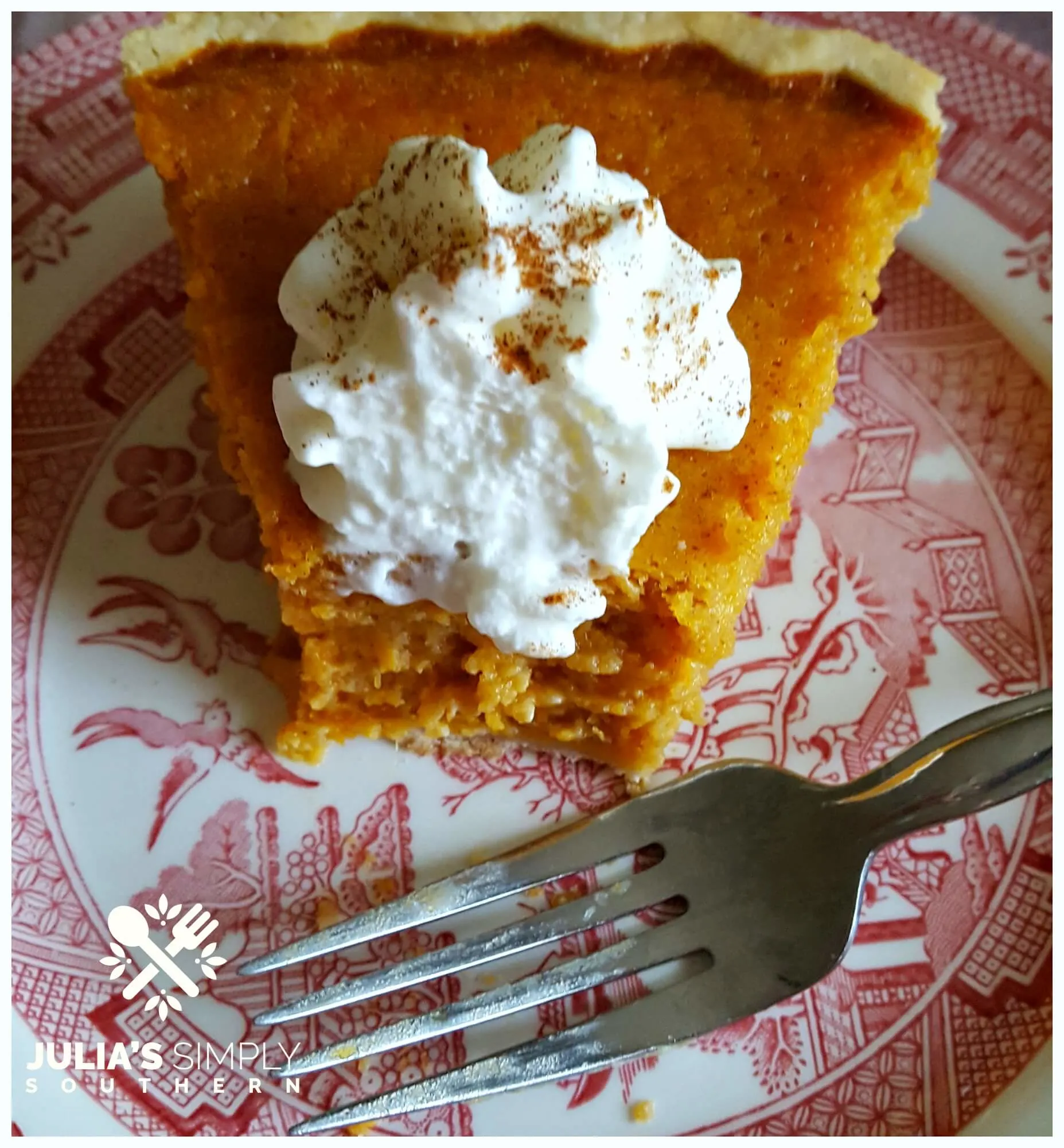 Delicious pie of Southern sweet potato pie topped with whipped cream on a red and white china plate