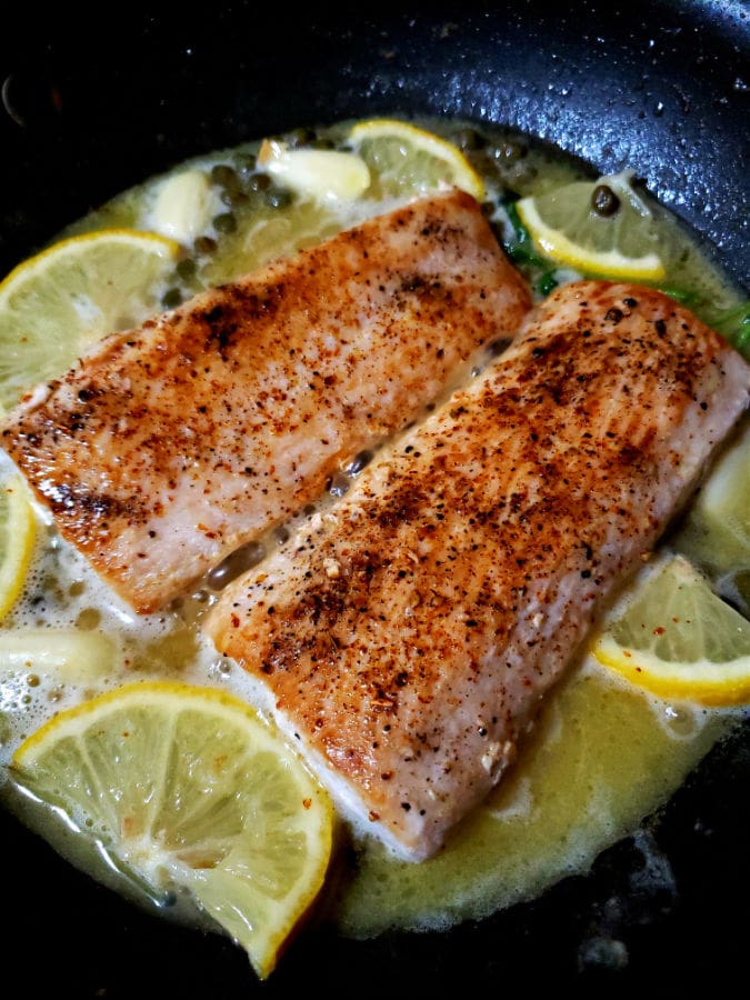 Two pieces of mahi mahi are being cooked in a skillet.