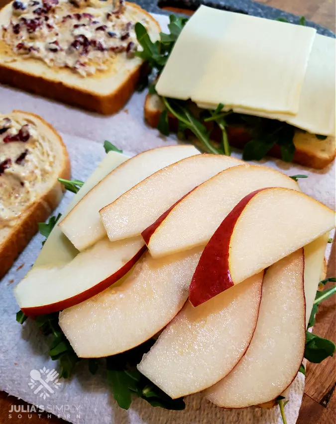 building turkey sandwiches with sliced pear, white cheddar, arugula and a cranberry spread