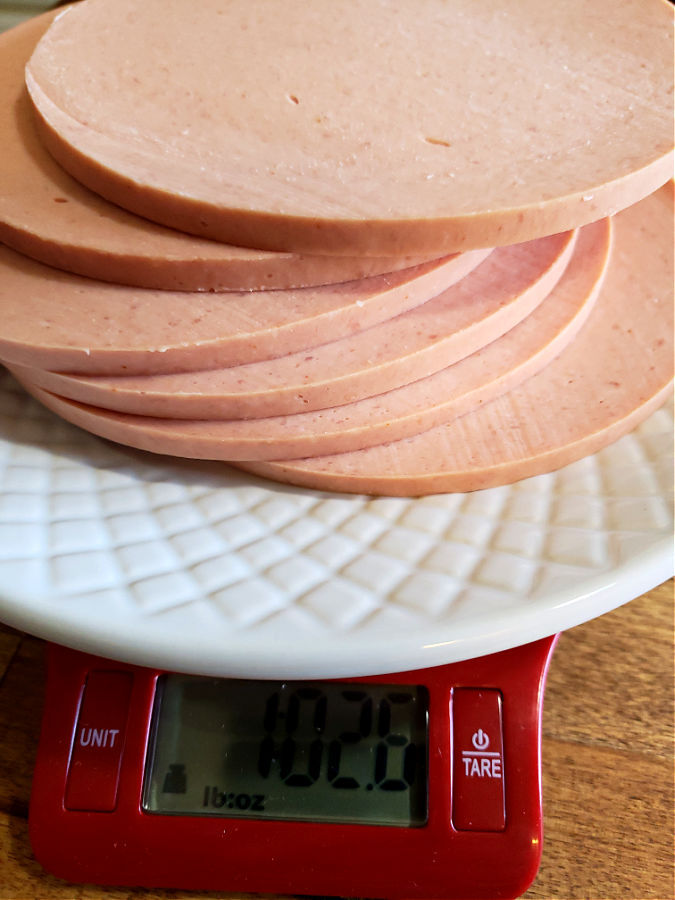 Measuring portion of sliced bologna for salad spread recipe