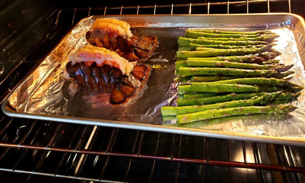 Sheet pan with lobster tails and asparagus for Broiled Lobster Tail Recipe