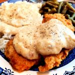 Herb Seasoned Southern Fried Boneless Chicken Breast on a plate with rice and gravy and green beans