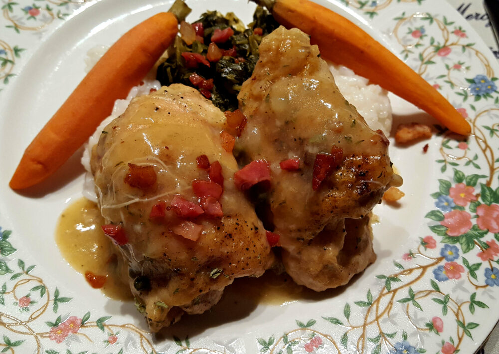 Braised Chicken Thighs on a dinner plate with carrots and greens