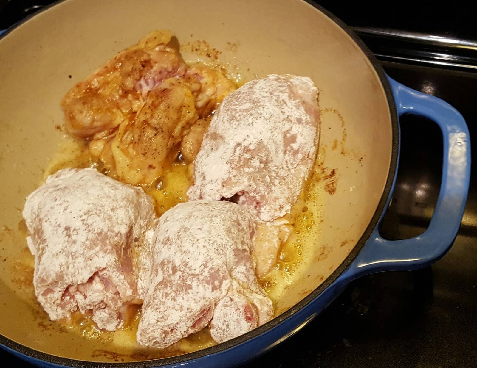 Browning chicken thighs in a lodge enamel cast iron casserole pot