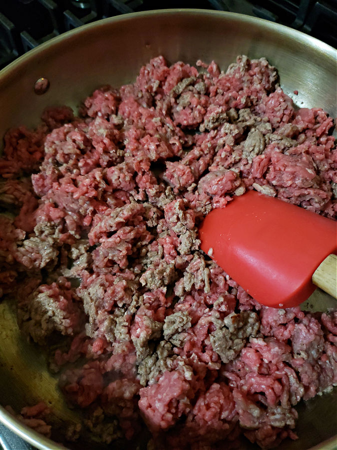Large skillet with ground beef cooking for hot dog chili