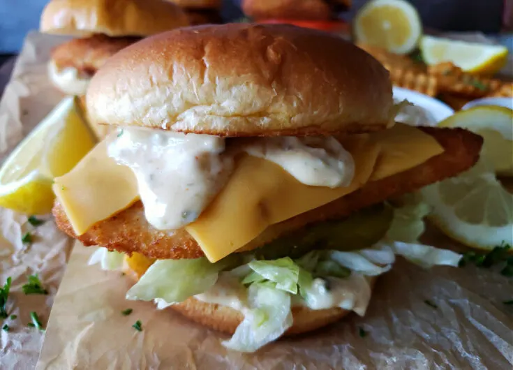 Air Fryer Fish Sandwich Deluxe with crispy filet, homemade tartar sauce, cheese and toppings on toasted brioche bun