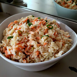 Traditional homemade southern coleslaw recipe in a white serving bowl on an antique serving buffet table
