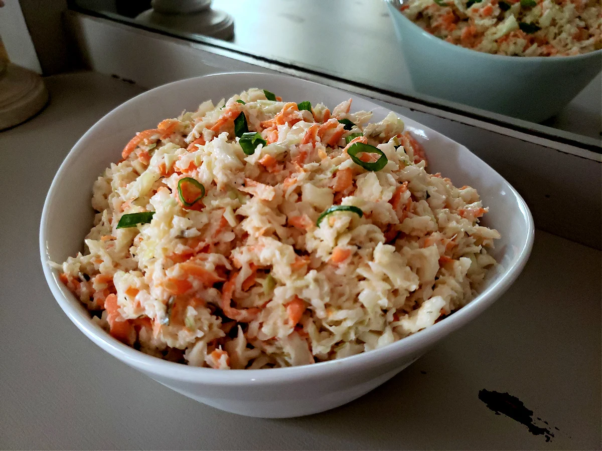 Traditional homemade southern coleslaw recipe in a white serving bowl on an antique serving buffet table