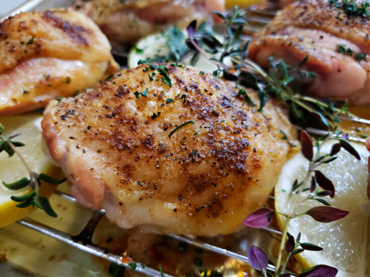 Recipes for chicken thighs: baked chicken thighs bone in with crispy skin and Greek seasoning on a rack lined sheet pan.