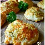 Garlic cheese drop biscuits brushed with an herb butter on a sheet of brown parchment with a few sprigs of parsley