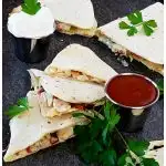 Photo of chicken bacon and ranch quesadillas served with sour cream and hot sauce and garnished with parsley