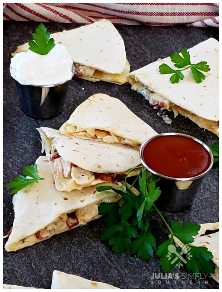 Photo of chicken bacon and ranch quesadillas served with sour cream and hot sauce and garnished with parsley