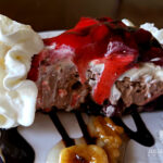 No Bake dessert - chocolate strawberry nut sundae pie on a plate with chocolate sauce, nuts and whipped cream garnish