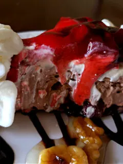 No Bake dessert - chocolate strawberry nut sundae pie on a plate with chocolate sauce, nuts and whipped cream garnish