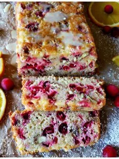 Cranberry Bread that has glaze and is dusted with confectioner's sugar and garnished with fresh cranberries and orange slices