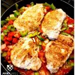 Creole Pork Chops Recipe in a cast iron skillet with the Cajun trinity and tomatoes